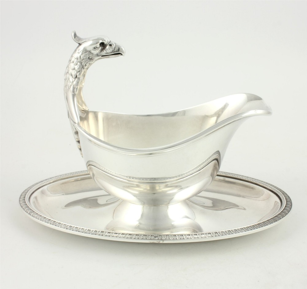 A silver-plated sauce boat featuring a sculpted eagle head handle set upon an integrated oval underplate.
