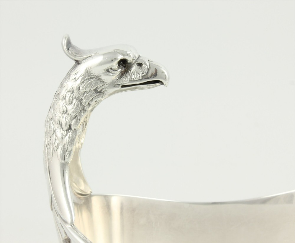 A silver-plated sauce boat featuring a sculpted eagle head handle set upon an integrated oval underplate. View V