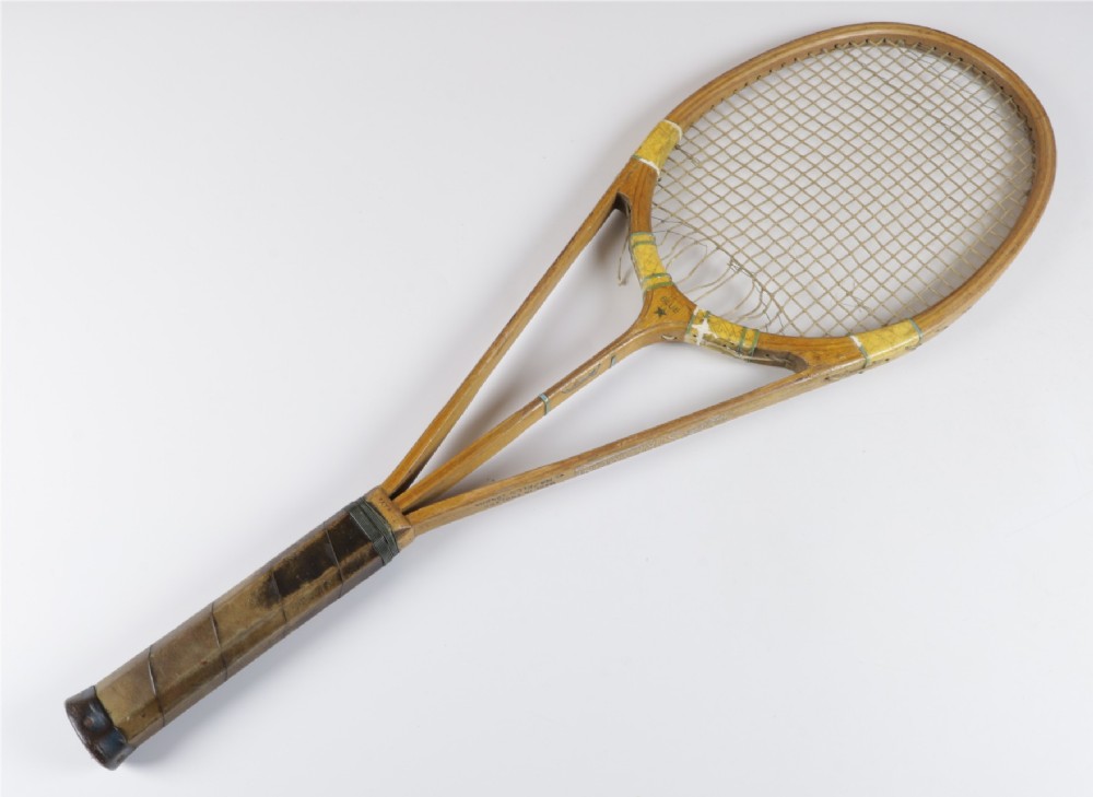 A 1930s Hazells Streamline wooden tennis racket with a triple shaft throat shown alongside a square wooden racket press. View VI