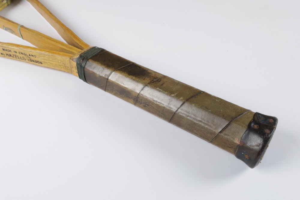 A 1930s Hazells Streamline wooden tennis racket with a triple shaft throat shown alongside a square wooden racket press. View IX