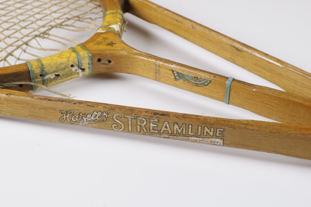 A 1930s Hazells Streamline wooden tennis racket with a triple shaft throat shown alongside a square wooden racket press. View XI