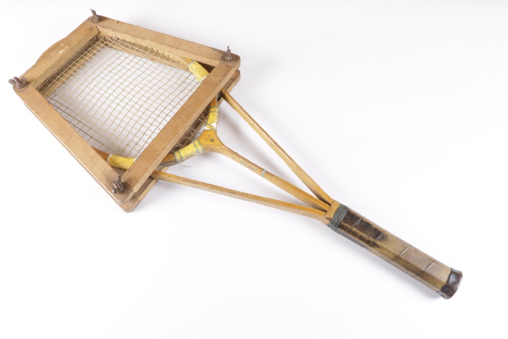 A 1930s Hazells Streamline wooden tennis racket with a triple shaft throat shown alongside a square wooden racket press. View XV