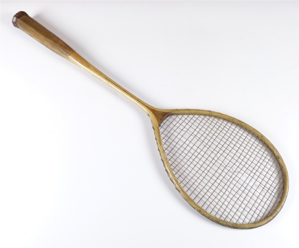 An antique Slazenger wooden badminton racket with a steam-bent frame, stringing, and a long wooden shaft.