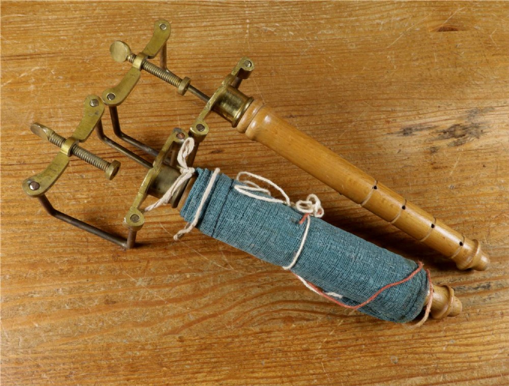 An open wooden pine box containing two vellum ping pong rackets, a white ball, and brass net clamps with a folded green net, featuring a Hamleys paper label inside the lid. View VIII