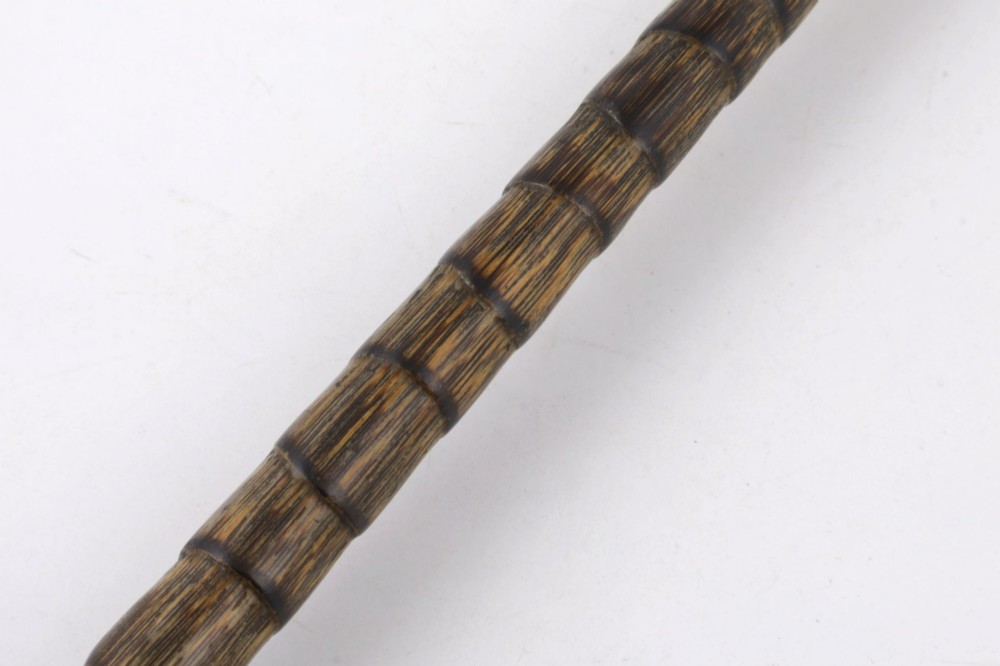 A close-up of an antique walking stick featuring a woven silver wire knot handle mounted on a dark bamboo shaft with a silver collar. View VII