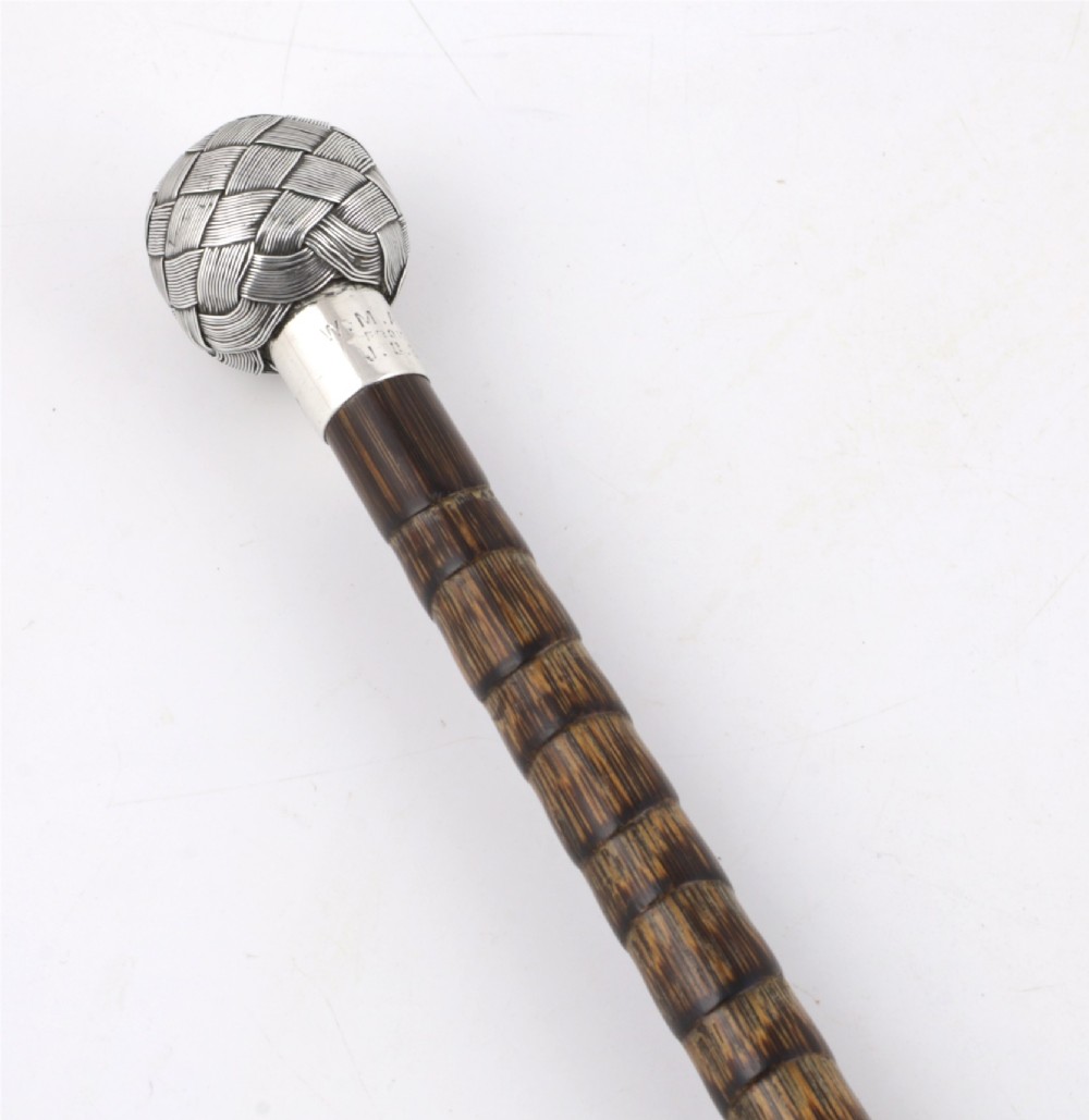 A close-up of an antique walking stick featuring a woven silver wire knot handle mounted on a dark bamboo shaft with a silver collar. View VIII