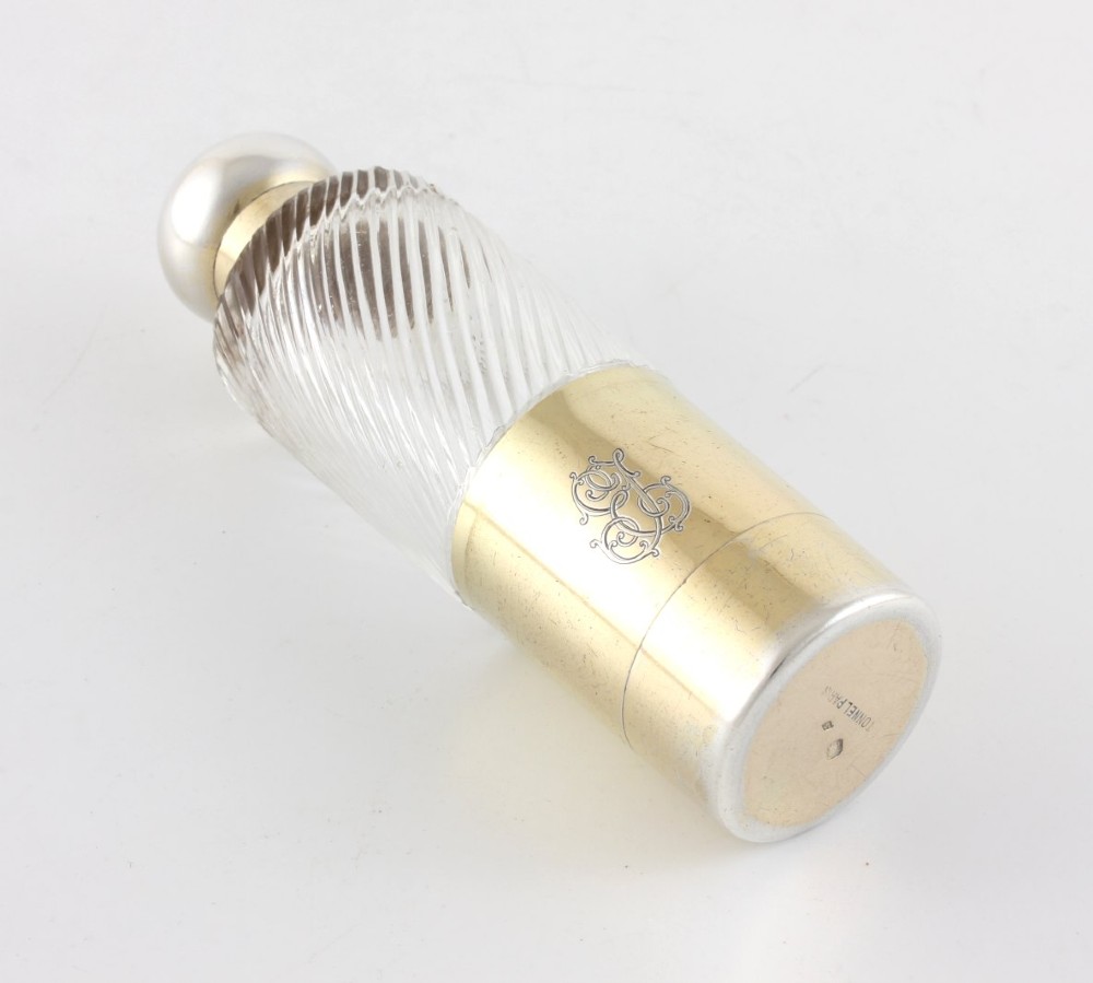 A cylindrical clear glass flask featuring spiral fluting, topped with a domed silver cap and a silver base bearing an engraved monogram. View IV