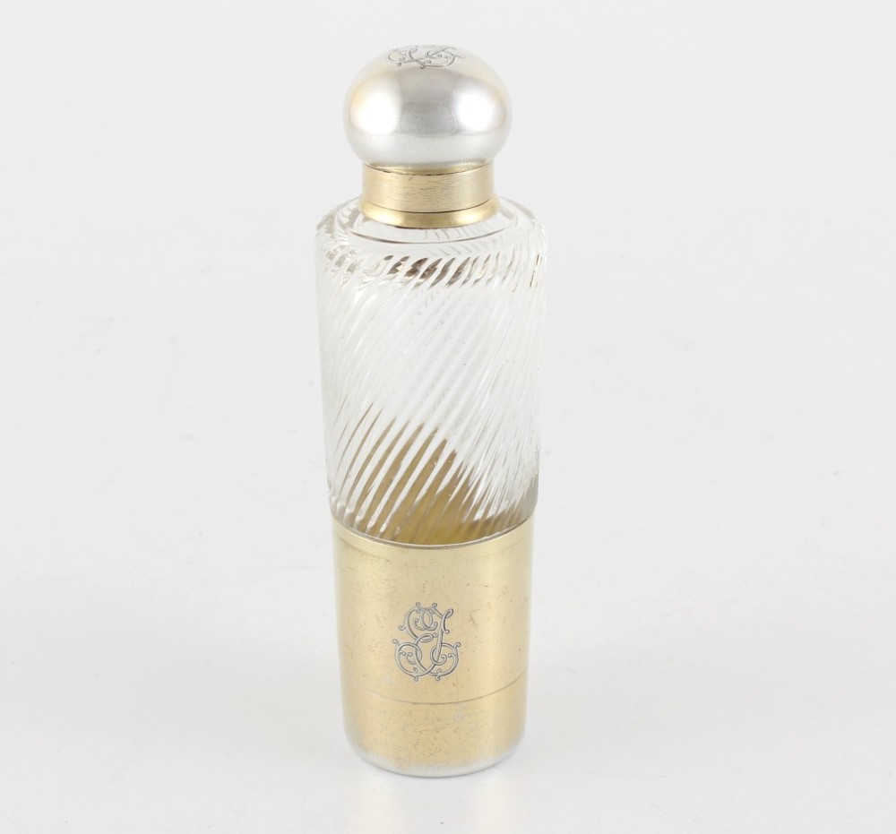 A cylindrical clear glass flask featuring spiral fluting, topped with a domed silver cap and a silver base bearing an engraved monogram. View X