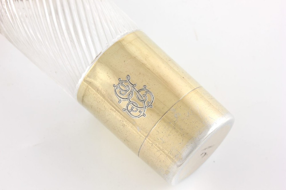 A cylindrical clear glass flask featuring spiral fluting, topped with a domed silver cap and a silver base bearing an engraved monogram. View XI
