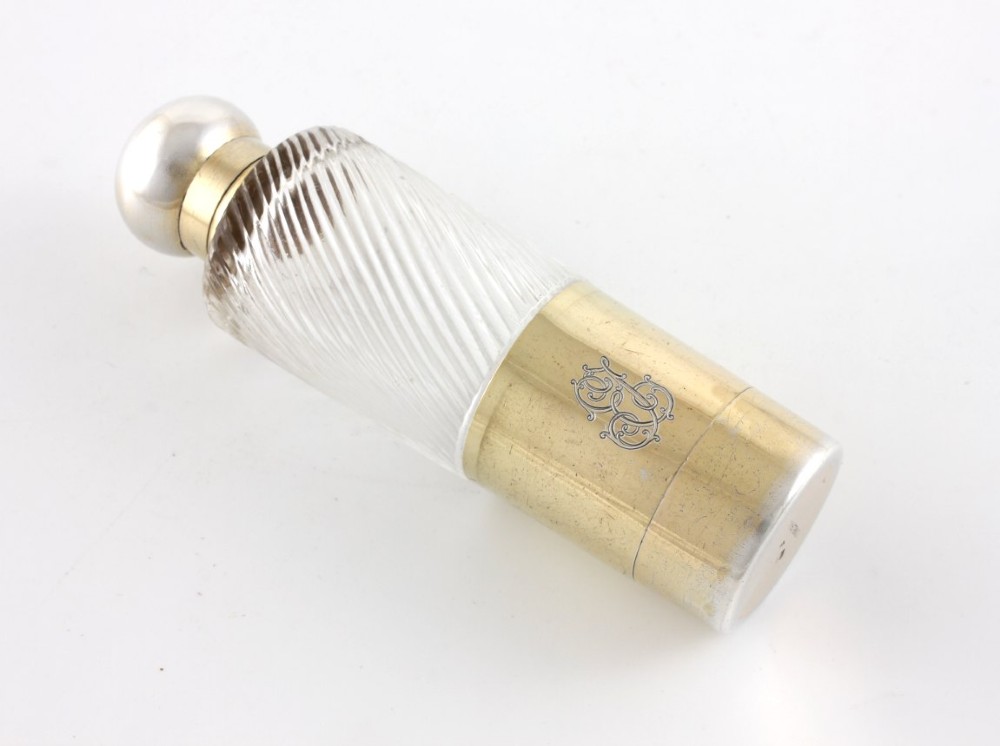 A cylindrical clear glass flask featuring spiral fluting, topped with a domed silver cap and a silver base bearing an engraved monogram. View XII