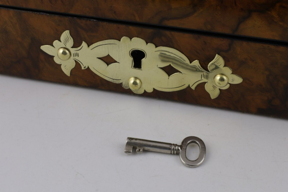 A domed burr walnut box featuring polished brass strapwork depicting three playing cards on the lid and a brass keyhole escutcheon on the front. View VII