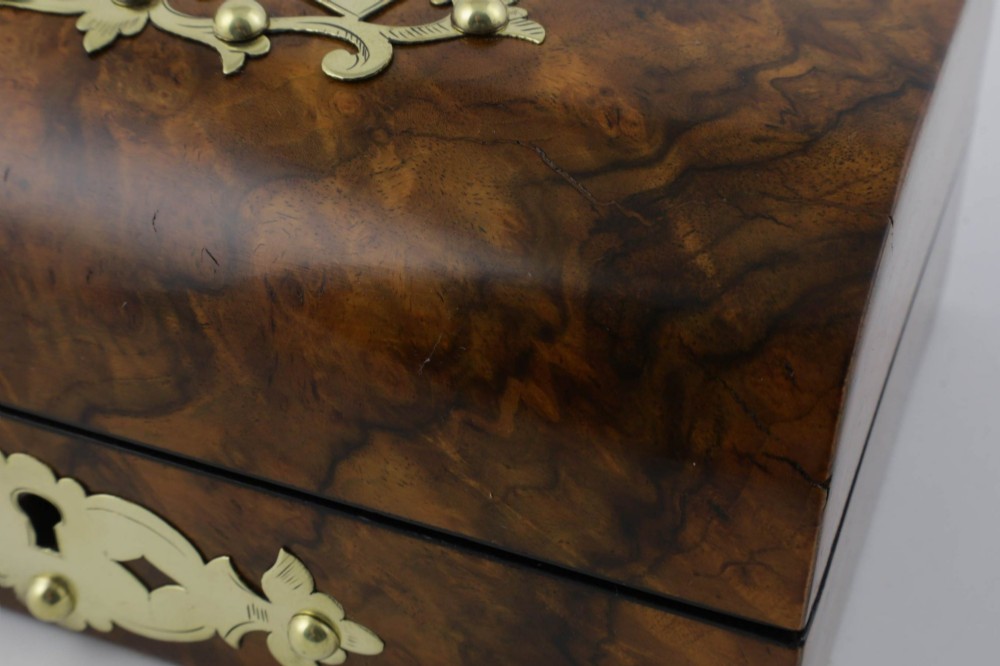 A domed burr walnut box featuring polished brass strapwork depicting three playing cards on the lid and a brass keyhole escutcheon on the front. View XIV