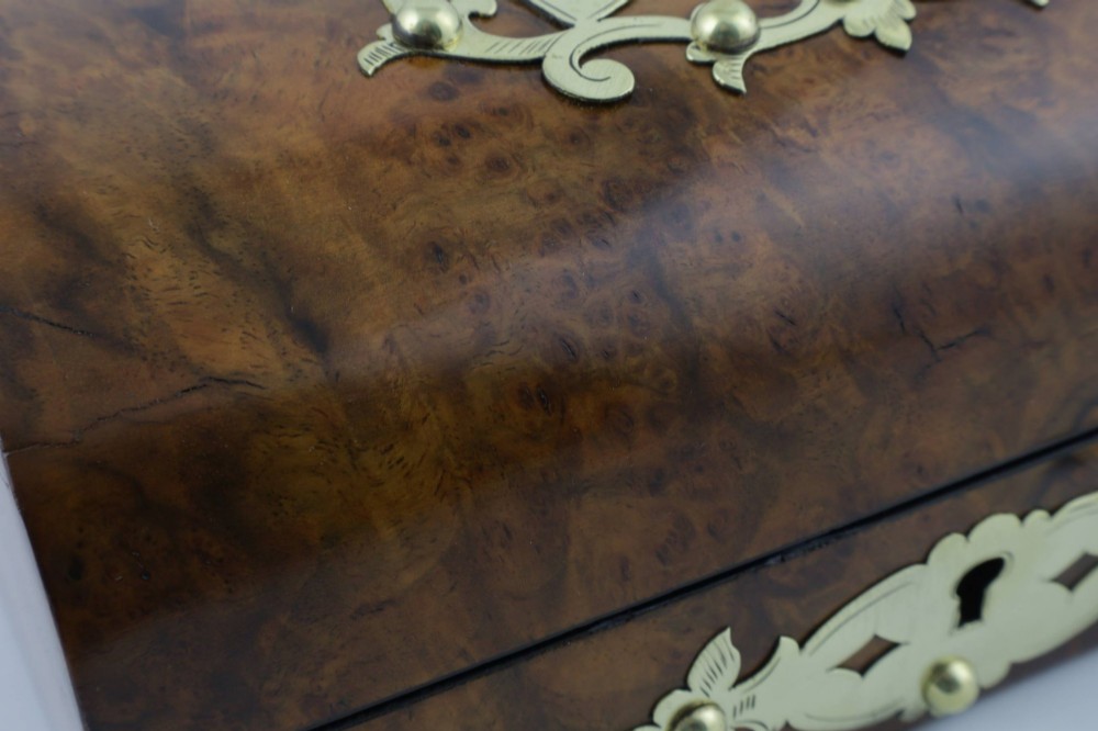 A domed burr walnut box featuring polished brass strapwork depicting three playing cards on the lid and a brass keyhole escutcheon on the front. View XV