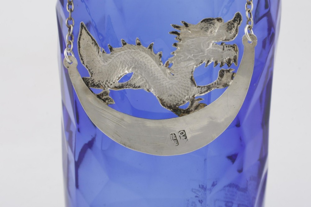 An antique Chinese silver decanter label depicting a chased dragon above a crescent plaque engraved with PORT, attached to a chain. View VII