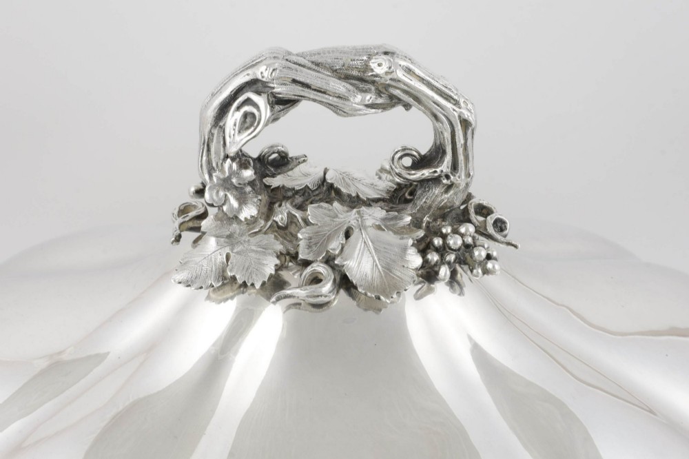 A Georgian Old Sheffield plate silver meat dome featuring a fluted body, an engraved heraldic coat of arms, and a cast handle adorned with vine leaves and grapes. View II