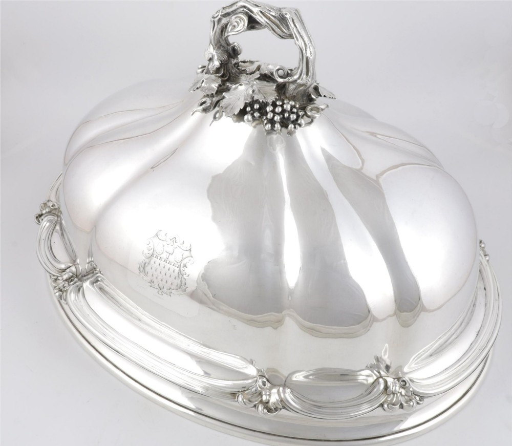 A Georgian Old Sheffield plate silver meat dome featuring a fluted body, an engraved heraldic coat of arms, and a cast handle adorned with vine leaves and grapes. View IV