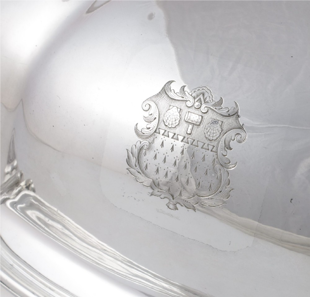 A Georgian Old Sheffield plate silver meat dome featuring a fluted body, an engraved heraldic coat of arms, and a cast handle adorned with vine leaves and grapes. View VI