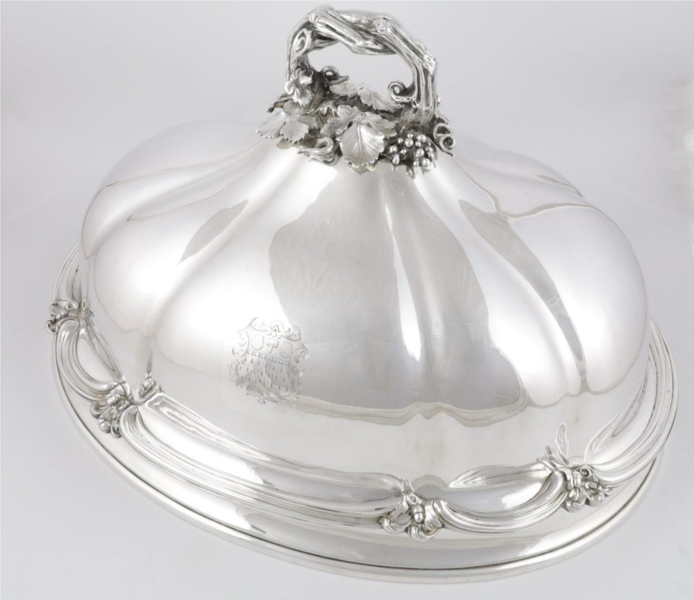 A Georgian Old Sheffield plate silver meat dome featuring a fluted body, an engraved heraldic coat of arms, and a cast handle adorned with vine leaves and grapes. View XI