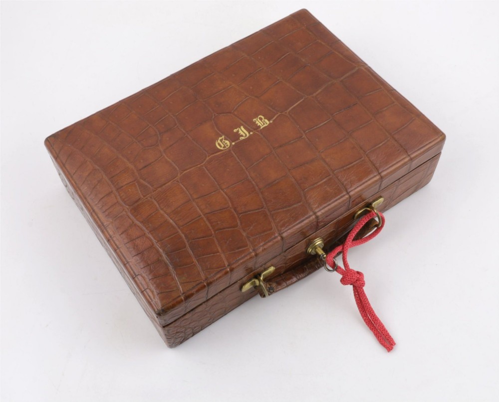 An open brown crocodile leather jewellery case featuring a green velvet lined interior with multiple compartments and brass lock hardware. View II