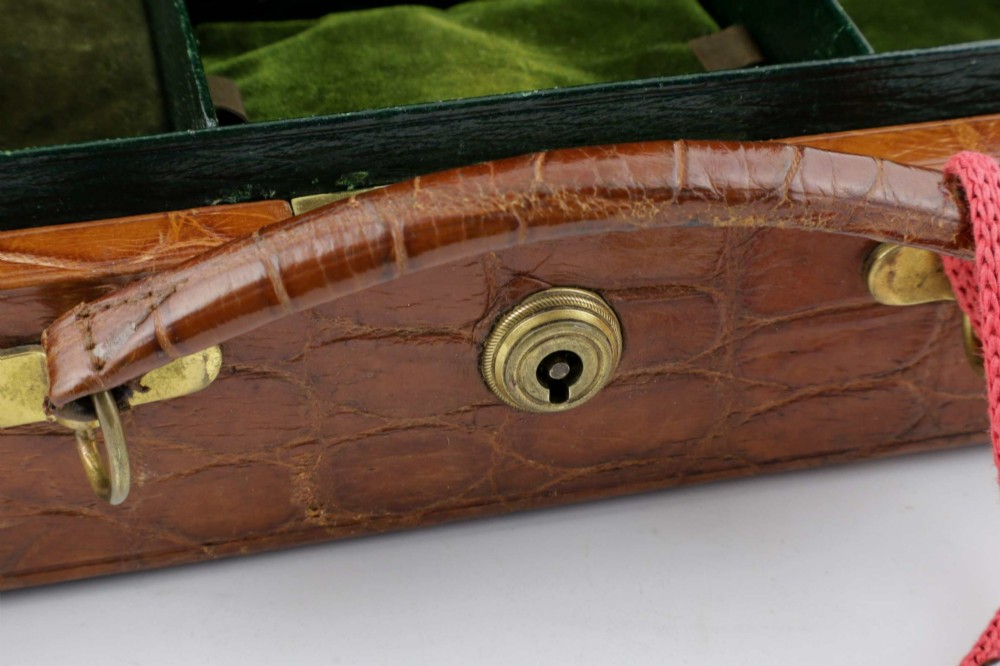 An open brown crocodile leather jewellery case featuring a green velvet lined interior with multiple compartments and brass lock hardware. View VII
