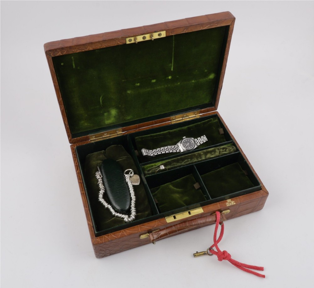 An open brown crocodile leather jewellery case featuring a green velvet lined interior with multiple compartments and brass lock hardware. View VIII