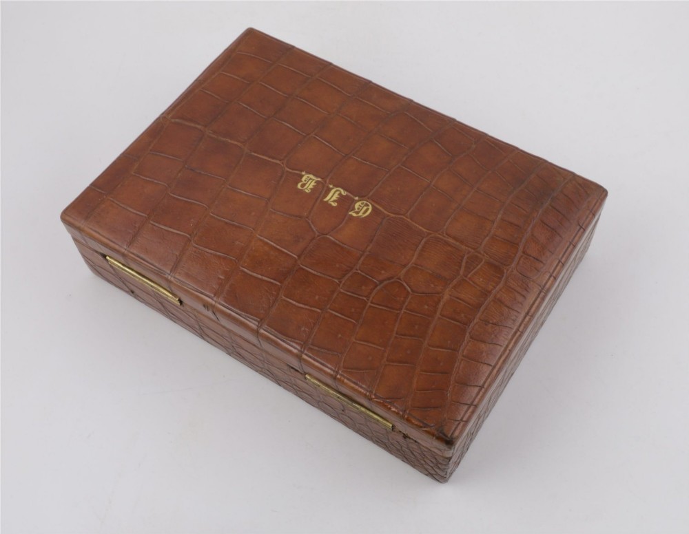 An open brown crocodile leather jewellery case featuring a green velvet lined interior with multiple compartments and brass lock hardware. View XIV