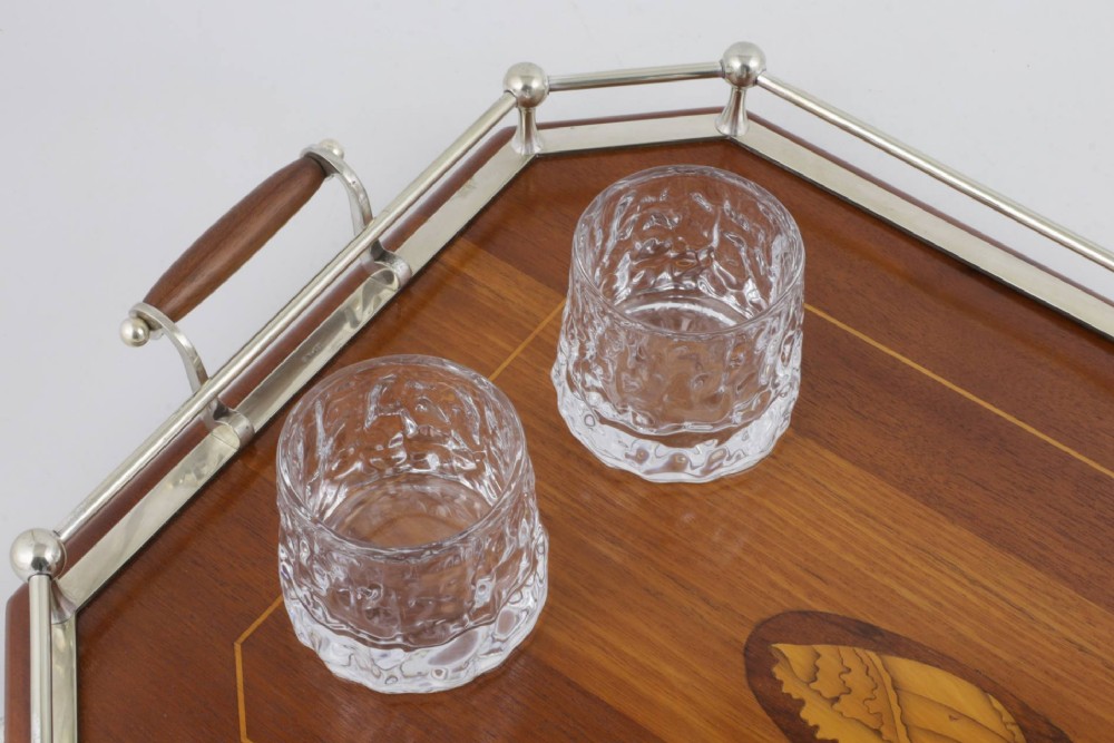 An octagonal brown wooden serving tray featuring a shell marquetry inlay and a polished silver-plated gallery rail. View VI
