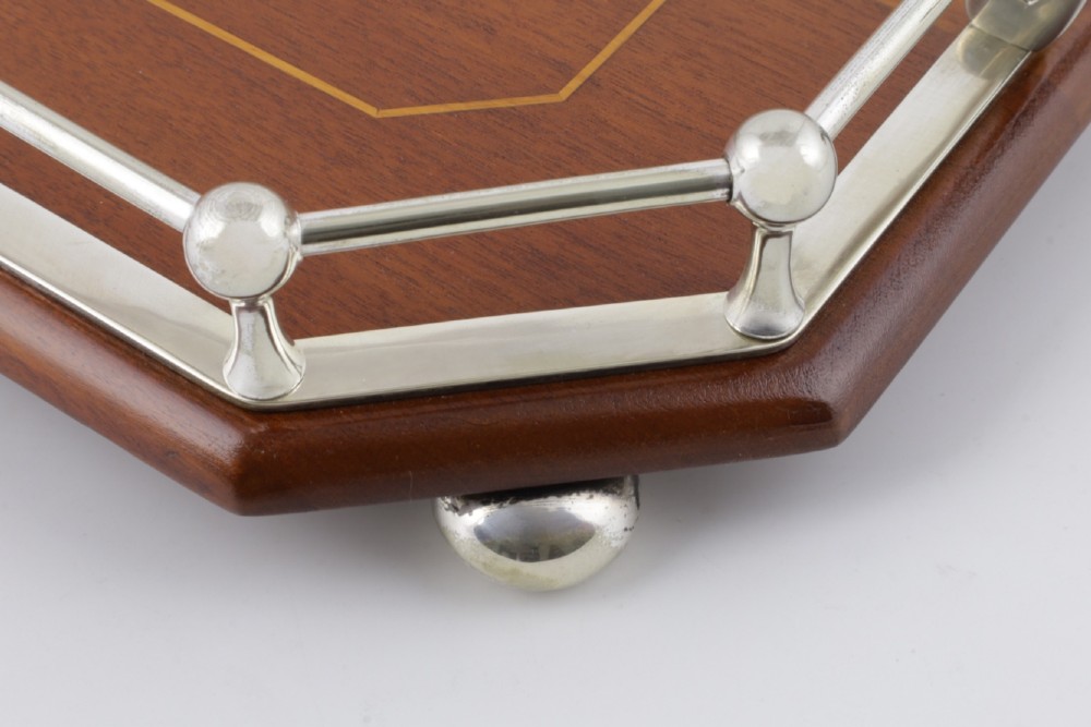 An octagonal brown wooden serving tray featuring a shell marquetry inlay and a polished silver-plated gallery rail. View IX