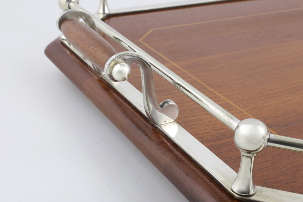 An octagonal brown wooden serving tray featuring a shell marquetry inlay and a polished silver-plated gallery rail. View XII