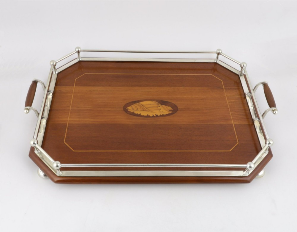 An octagonal brown wooden serving tray featuring a shell marquetry inlay and a polished silver-plated gallery rail. View XIV