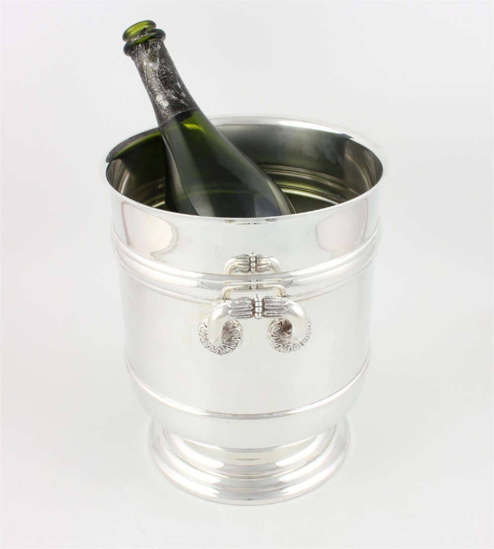A polished silver-plated champagne cooler featuring side handles with leaf detailing and a stepped pedestal base. View II