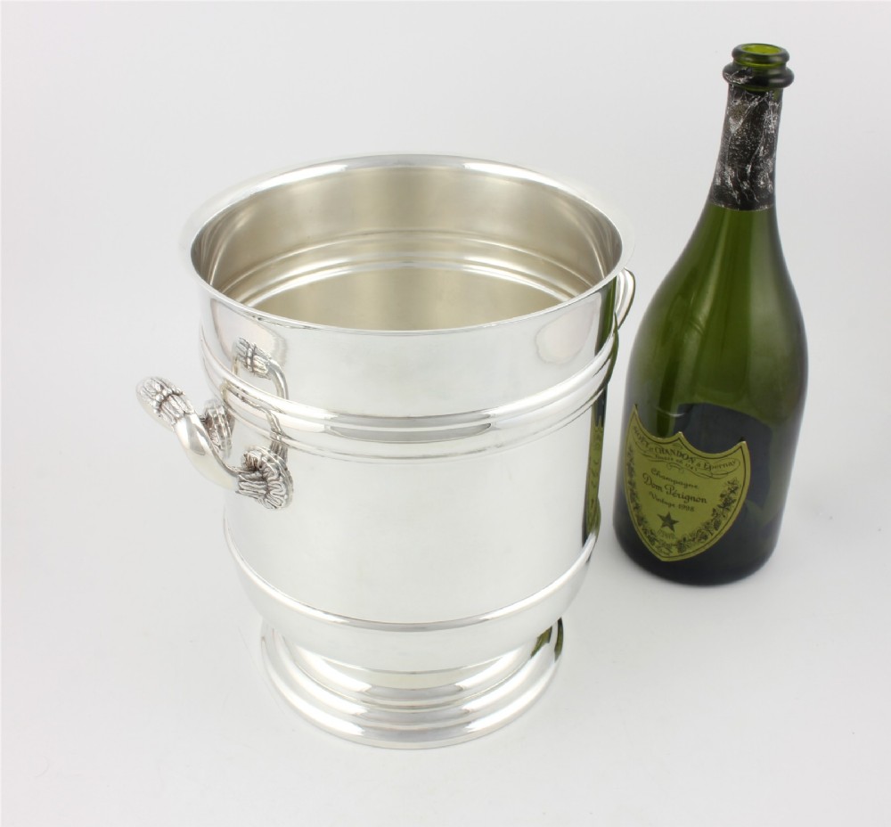 A polished silver-plated champagne cooler featuring side handles with leaf detailing and a stepped pedestal base. View VI