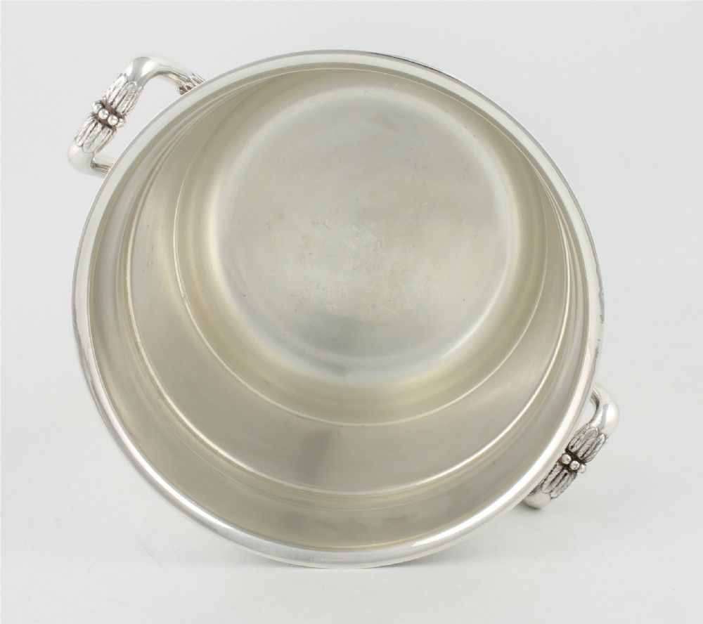 A polished silver-plated champagne cooler featuring side handles with leaf detailing and a stepped pedestal base. View VII