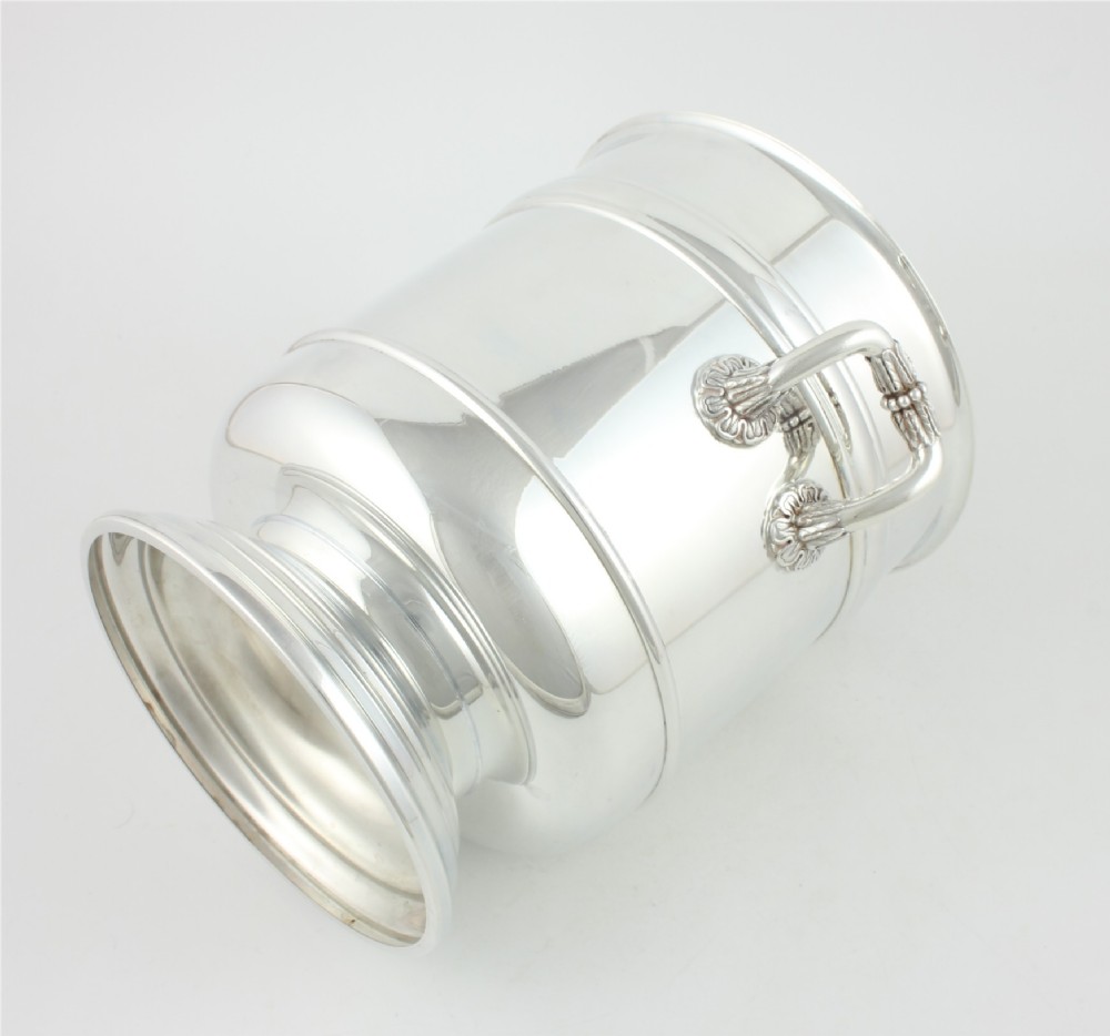 A polished silver-plated champagne cooler featuring side handles with leaf detailing and a stepped pedestal base. View X