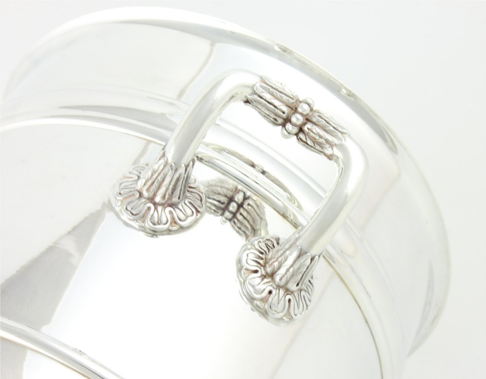 A polished silver-plated champagne cooler featuring side handles with leaf detailing and a stepped pedestal base. View XII