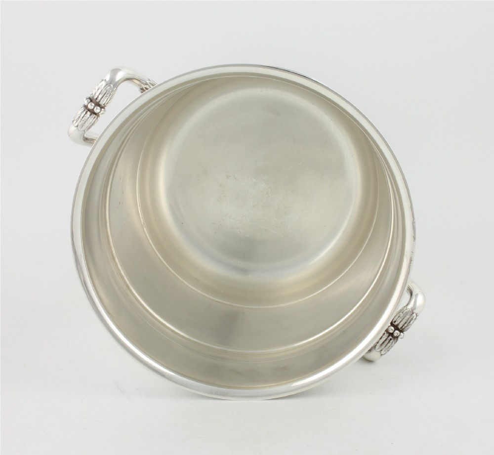 A polished silver-plated champagne cooler featuring side handles with leaf detailing and a stepped pedestal base. View XIII