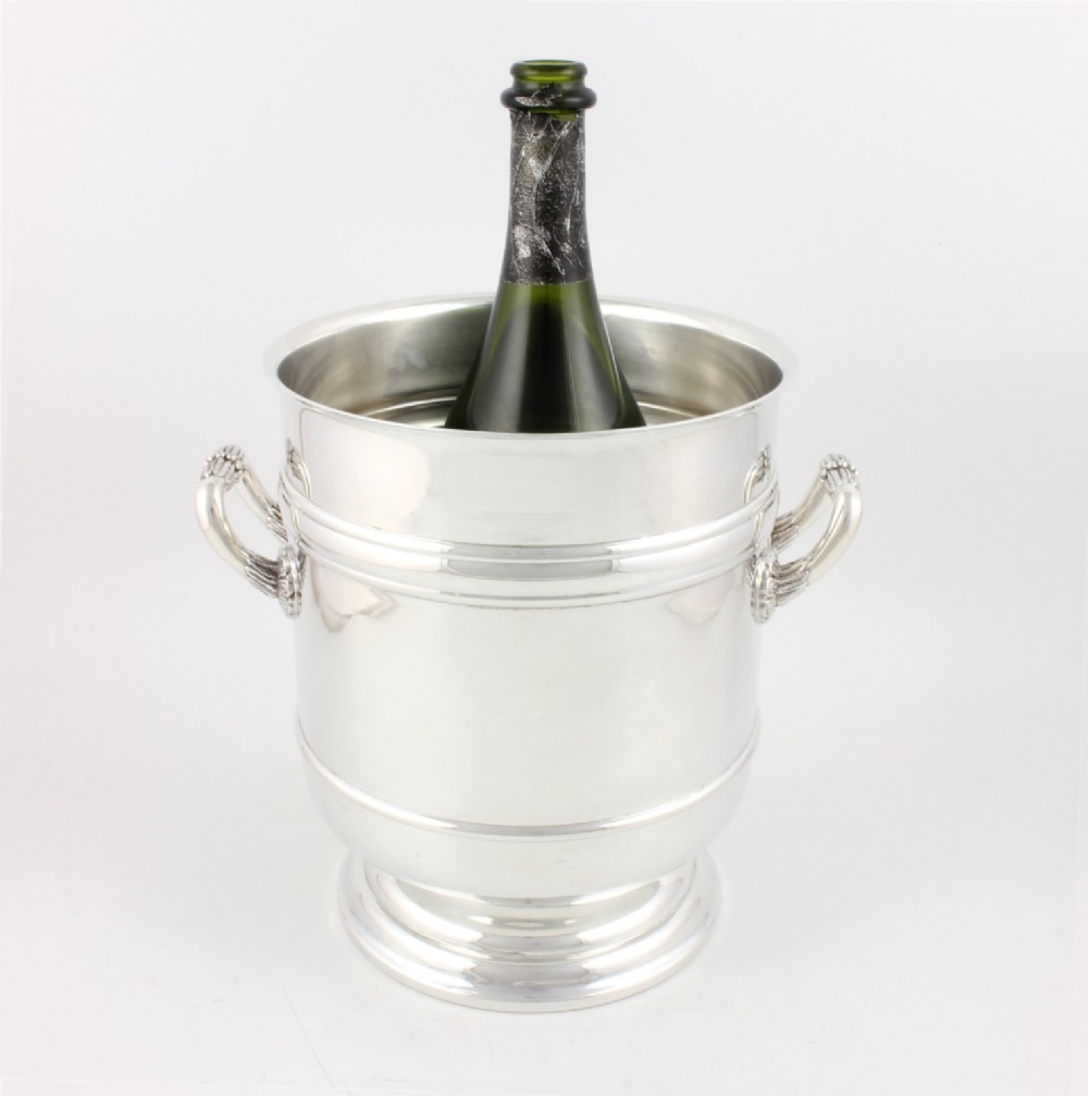 A polished silver-plated champagne cooler featuring side handles with leaf detailing and a stepped pedestal base. View XIV