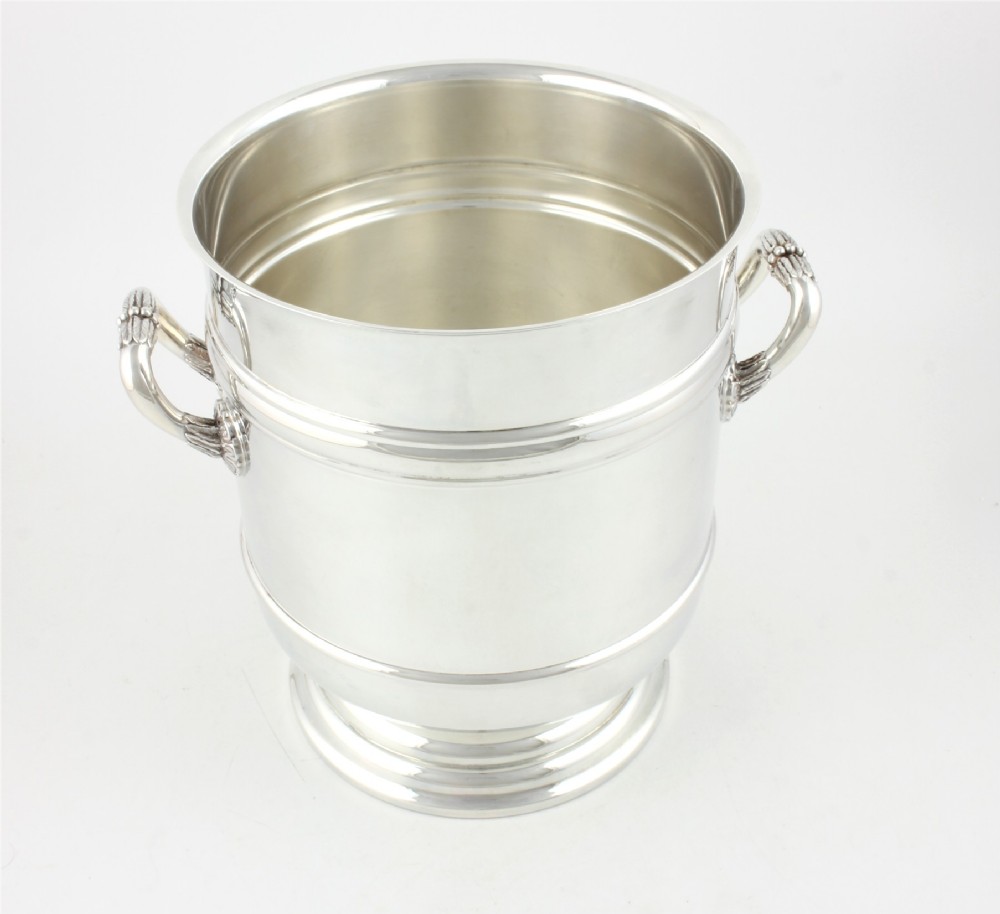 A polished silver-plated champagne cooler featuring side handles with leaf detailing and a stepped pedestal base. View XV