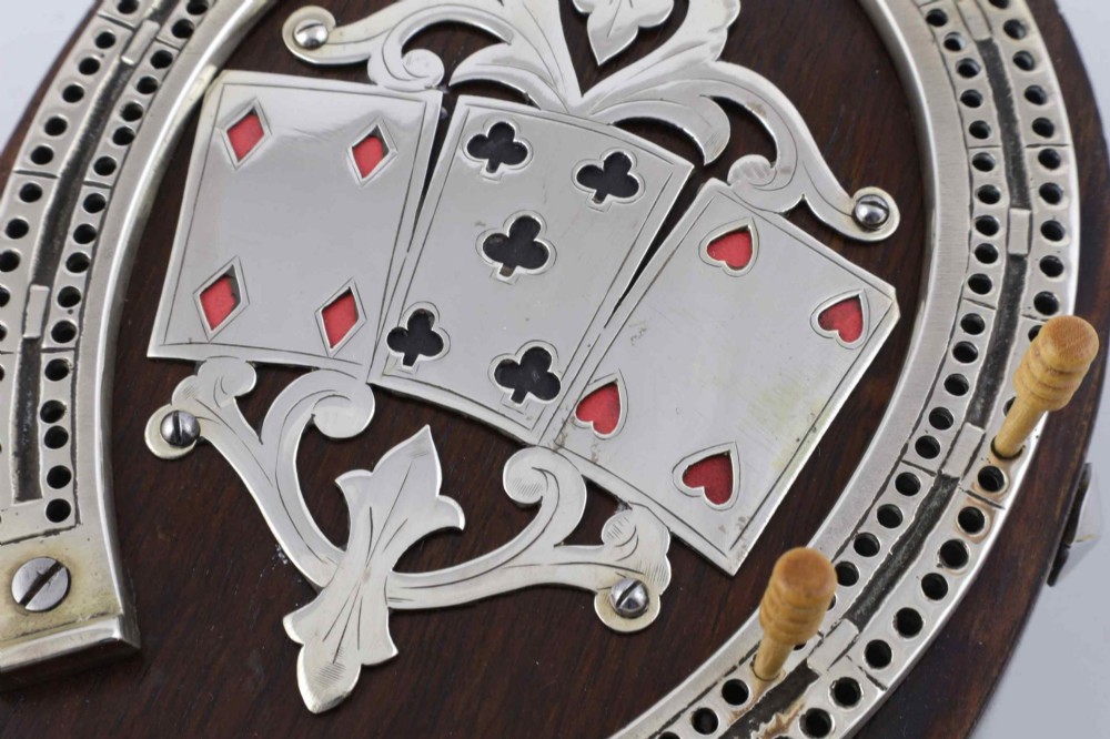 An antique horseshoe-shaped dark oak games box featuring silver metal scrollwork, playing card motifs, and an integrated cribbage scoring track. View IV