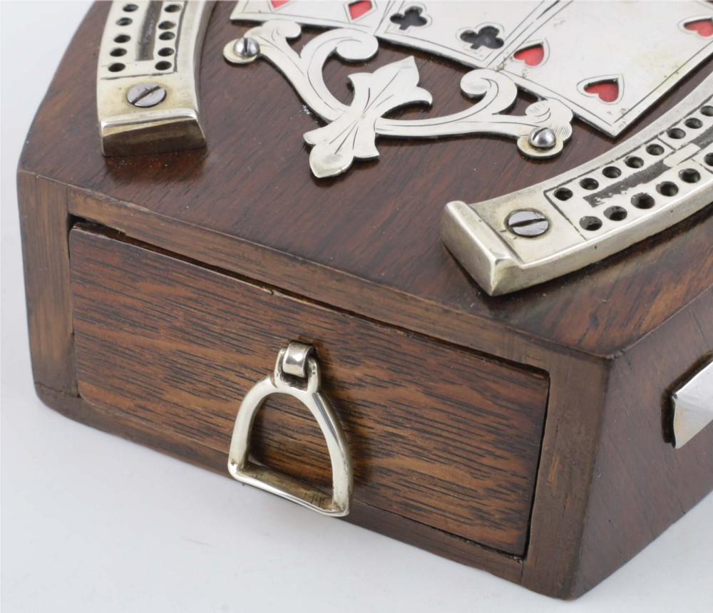 An antique horseshoe-shaped dark oak games box featuring silver metal scrollwork, playing card motifs, and an integrated cribbage scoring track. View XI