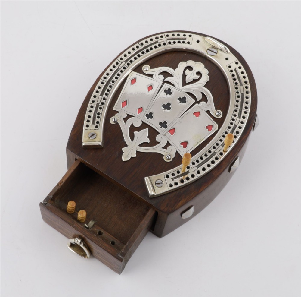 An antique horseshoe-shaped dark oak games box featuring silver metal scrollwork, playing card motifs, and an integrated cribbage scoring track. View XII
