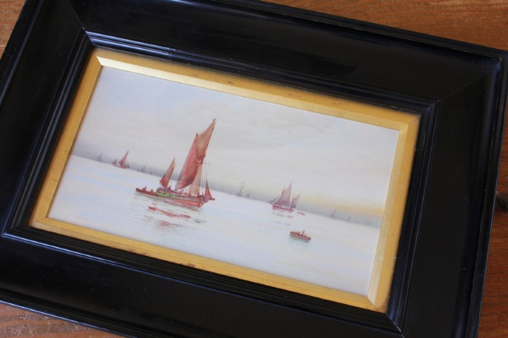 A framed early twentieth-century watercolour painting featuring red-sailed fishing boats on calm waters off Scarborough, enclosed in a thick black frame with a gold inner slip. View IV