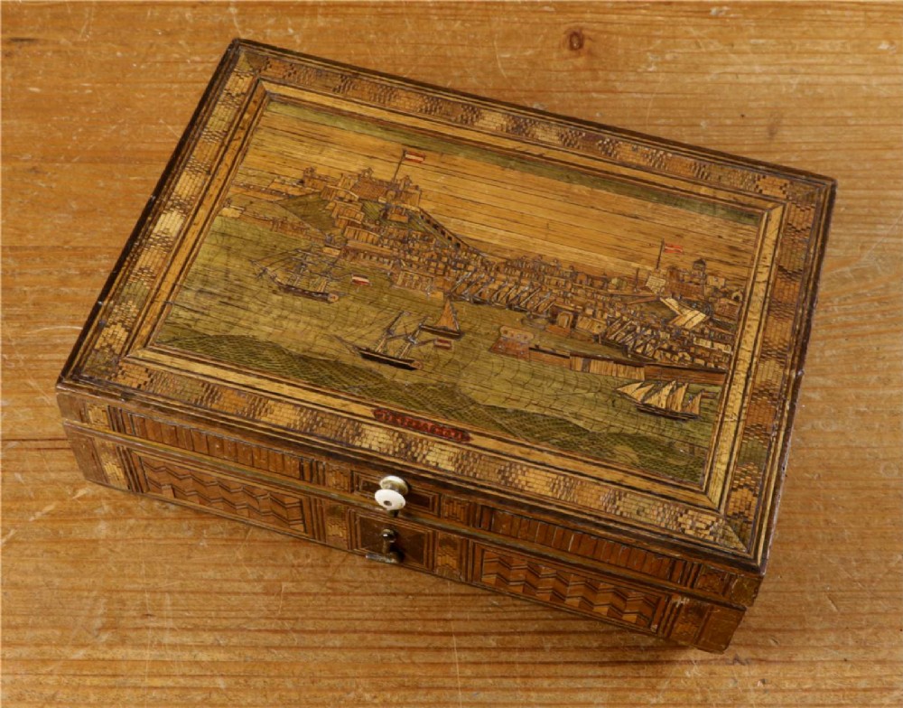 A rectangular wooden box top featuring intricate straw marquetry depicting a harbour landscape with ships, fortresses, and geometric borders. View III