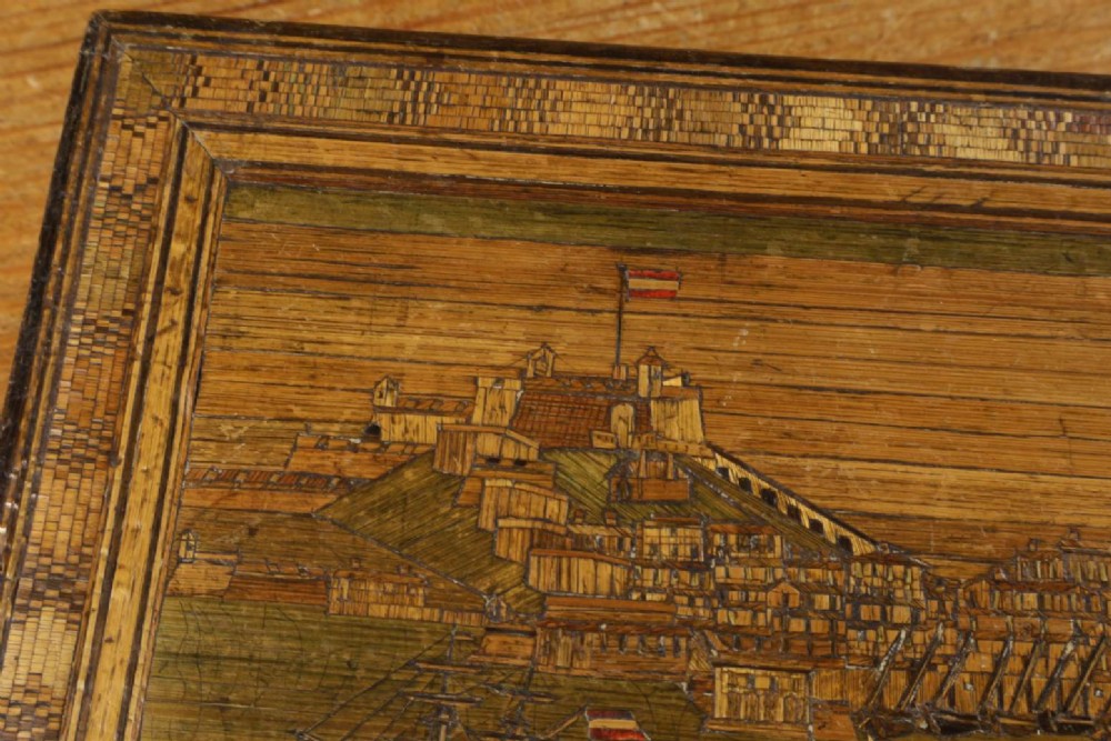 A rectangular wooden box top featuring intricate straw marquetry depicting a harbour landscape with ships, fortresses, and geometric borders. View V