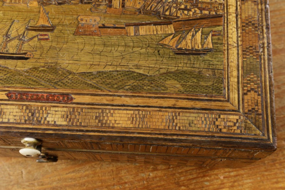 A rectangular wooden box top featuring intricate straw marquetry depicting a harbour landscape with ships, fortresses, and geometric borders. View VIII