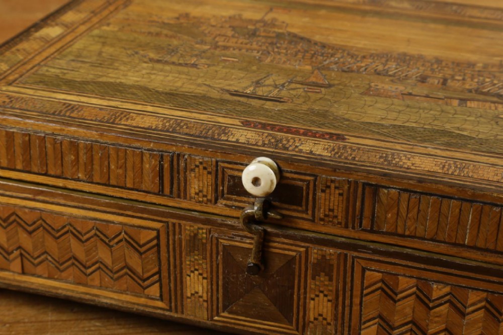 A rectangular wooden box top featuring intricate straw marquetry depicting a harbour landscape with ships, fortresses, and geometric borders. View XIII