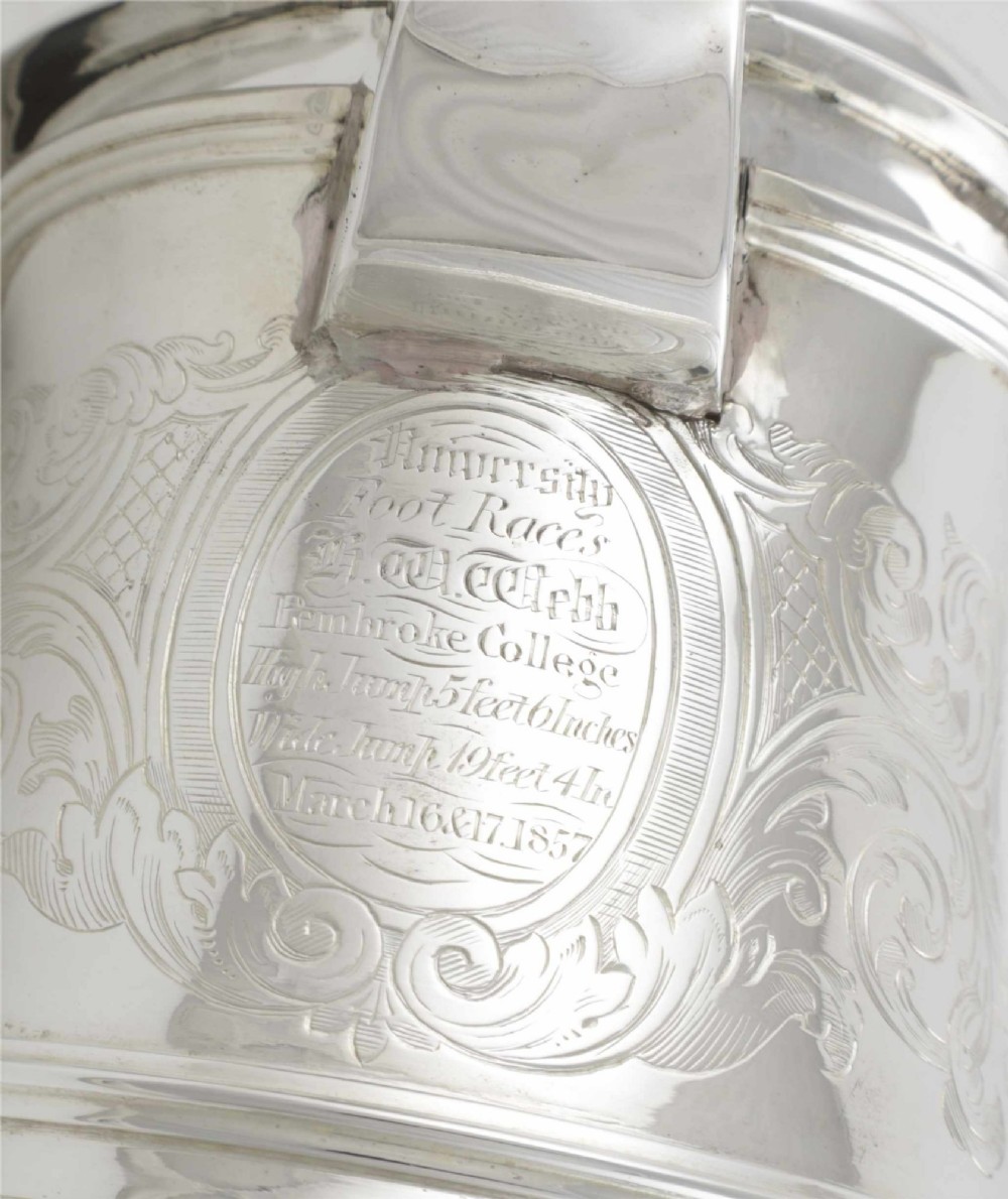An engraved silver lidded jug featuring a hinged cap, scrolling handle, and foliate engraving across the body. View II