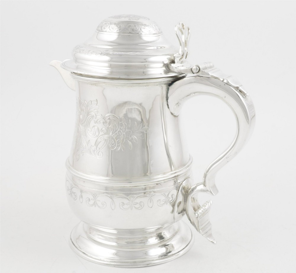 An engraved silver lidded jug featuring a hinged cap, scrolling handle, and foliate engraving across the body. View VI