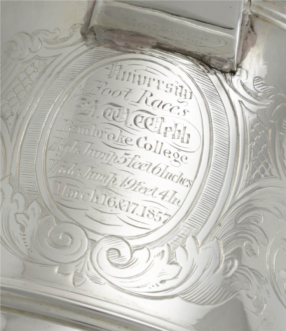 An engraved silver lidded jug featuring a hinged cap, scrolling handle, and foliate engraving across the body. View XI