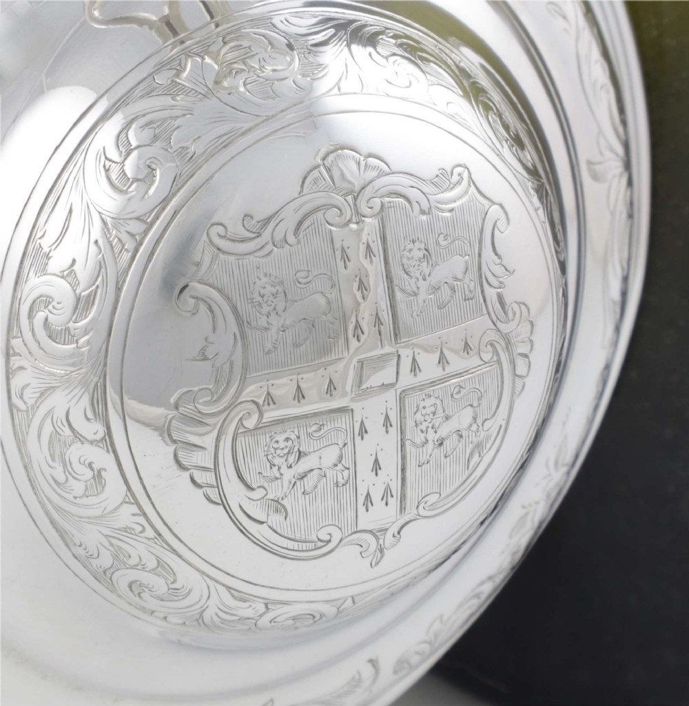 An engraved silver lidded jug featuring a hinged cap, scrolling handle, and foliate engraving across the body. View XII